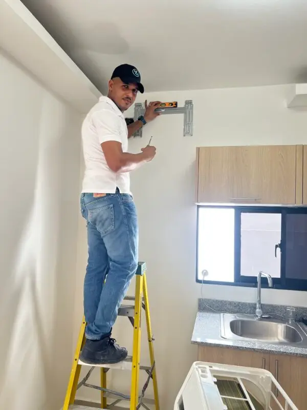 Técnico de Aires Daury sobre una escalera fijando el soporte de un mini split